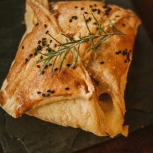 A deliciously baked chicken pastry garnished with rosemary and sesame.