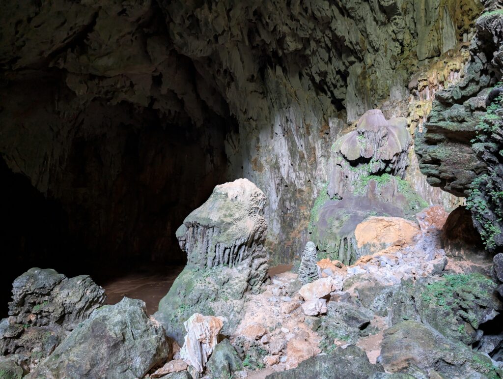 Explore the magnificent limestone formations with stalactites and stalagmites inside a vast, ancient cave.